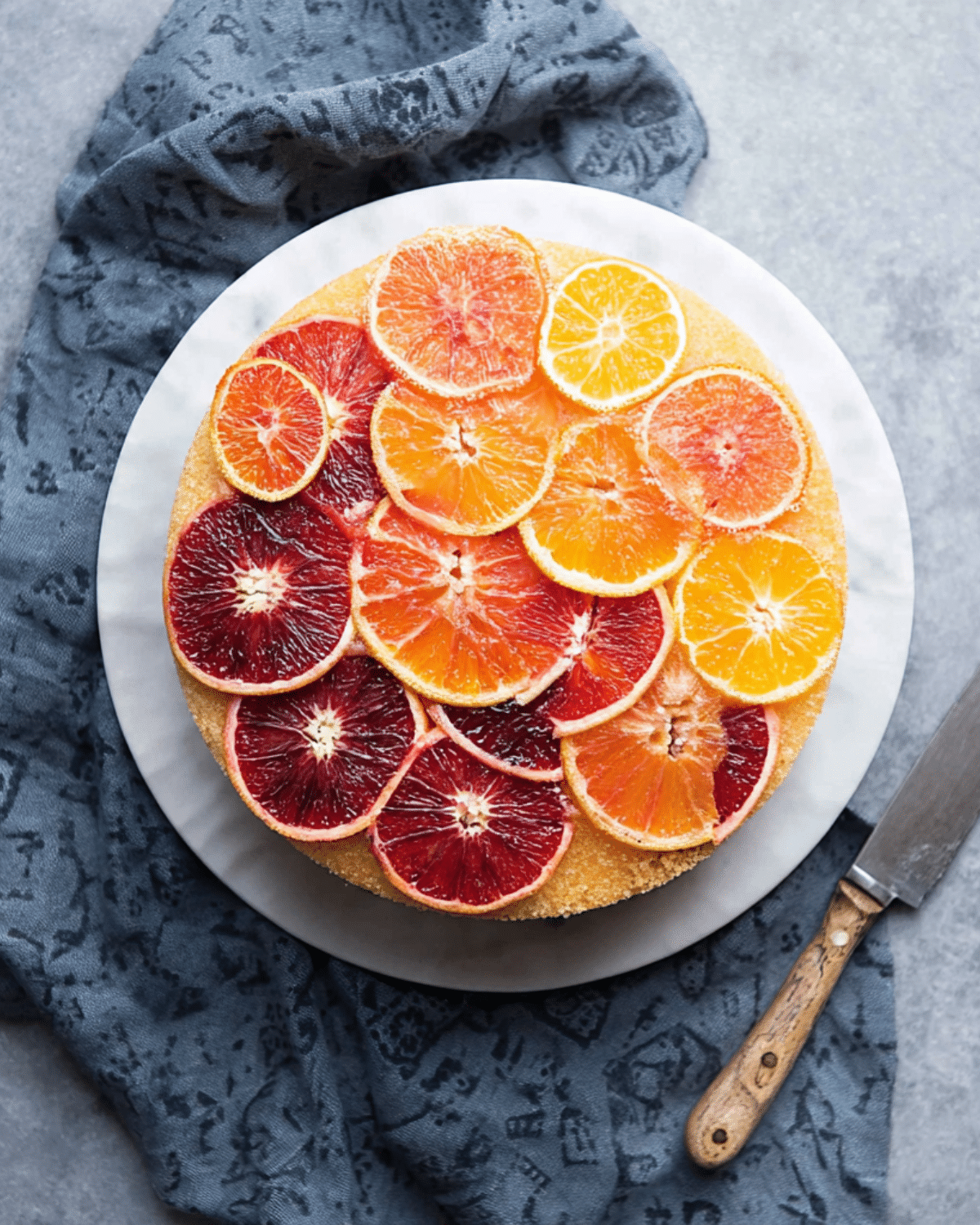 Upside-down ombré citrus cake topped with vibrant slices of blood oranges, navels, and lemons arranged in a gradient.