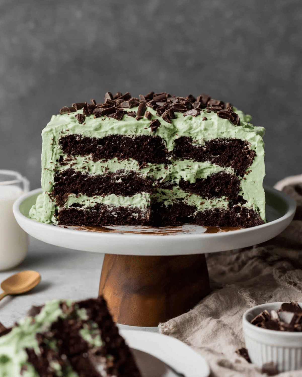 A layered Andes chocolate mint dessert cake with dark chocolate cake layers, mint green frosting, and topped with chopped Andes mints.