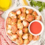 A plate of crispy Air Fryer Crab Bites served with dipping sauce and garnished with herbs.