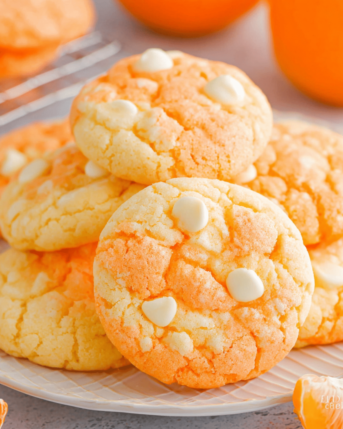 Stack of orange and white swirled creamsicle cookies with white chocolate chips on a plate.