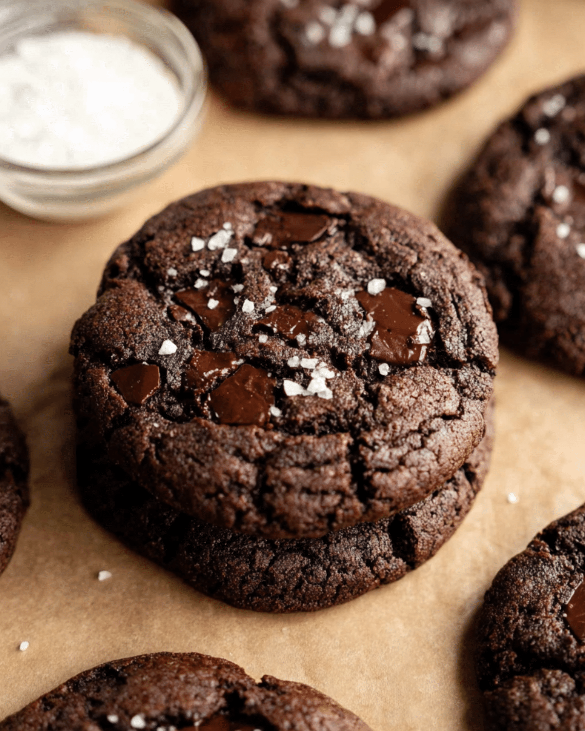 A stack of triple chocolate cookies with gooey chocolate chunks and a sprinkle of sea salt on top.