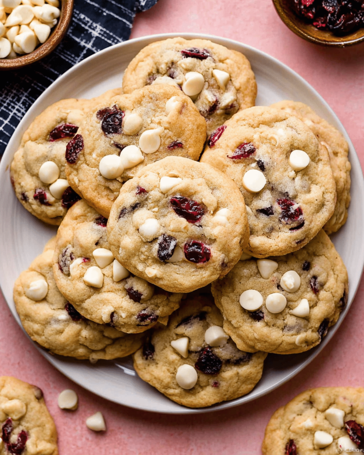A plate full of white chocolate cranberry cookies, packed with white chocolate chips and dried cranberries.