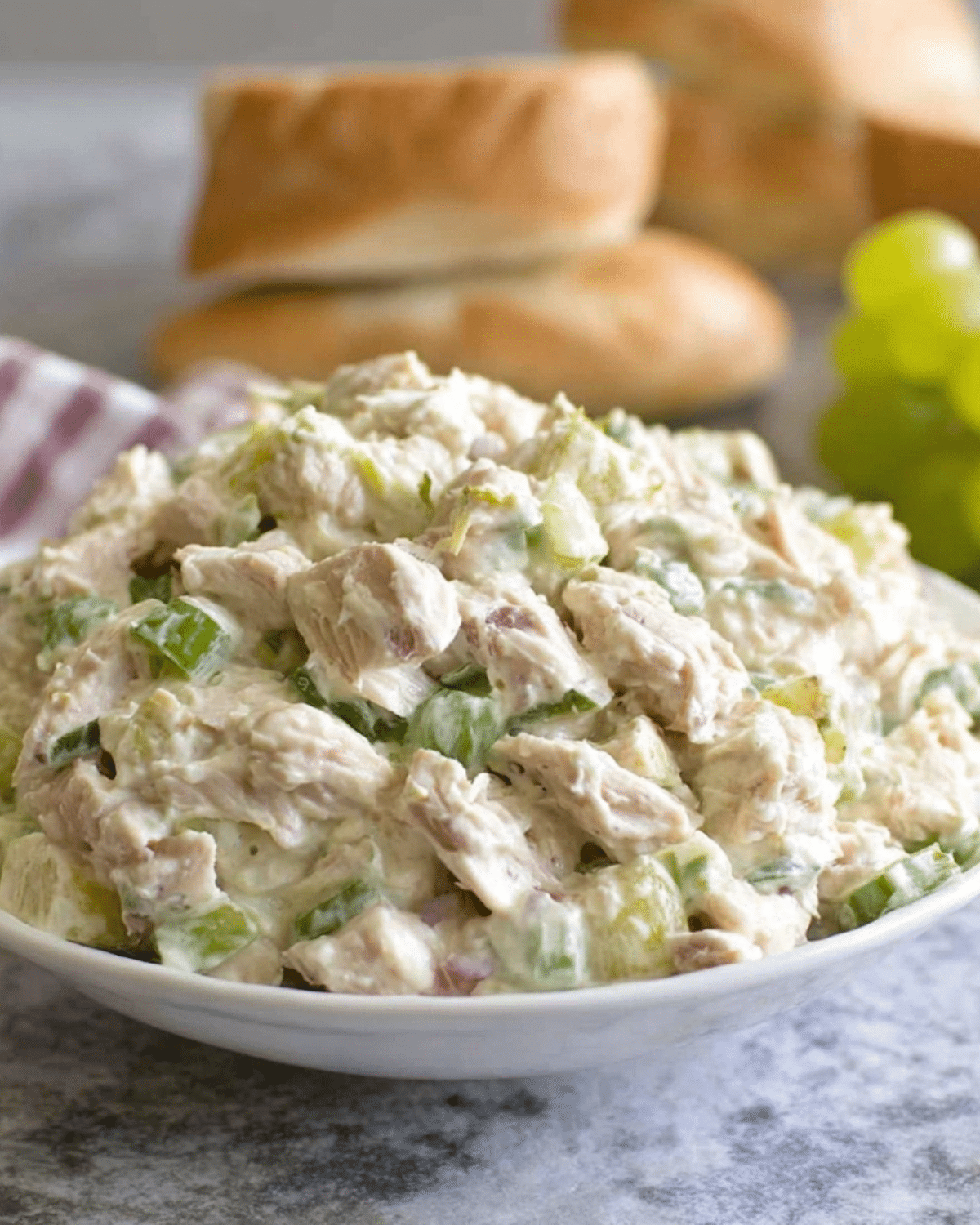 Bowl of creamy Chicken Salad filled with chunks of chicken, chopped celery, green grapes, and a mayonnaise-based dressing.