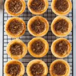 Classic Butter Tarts with golden crusts and gooey brown sugar filling cooling on a wire rack.
