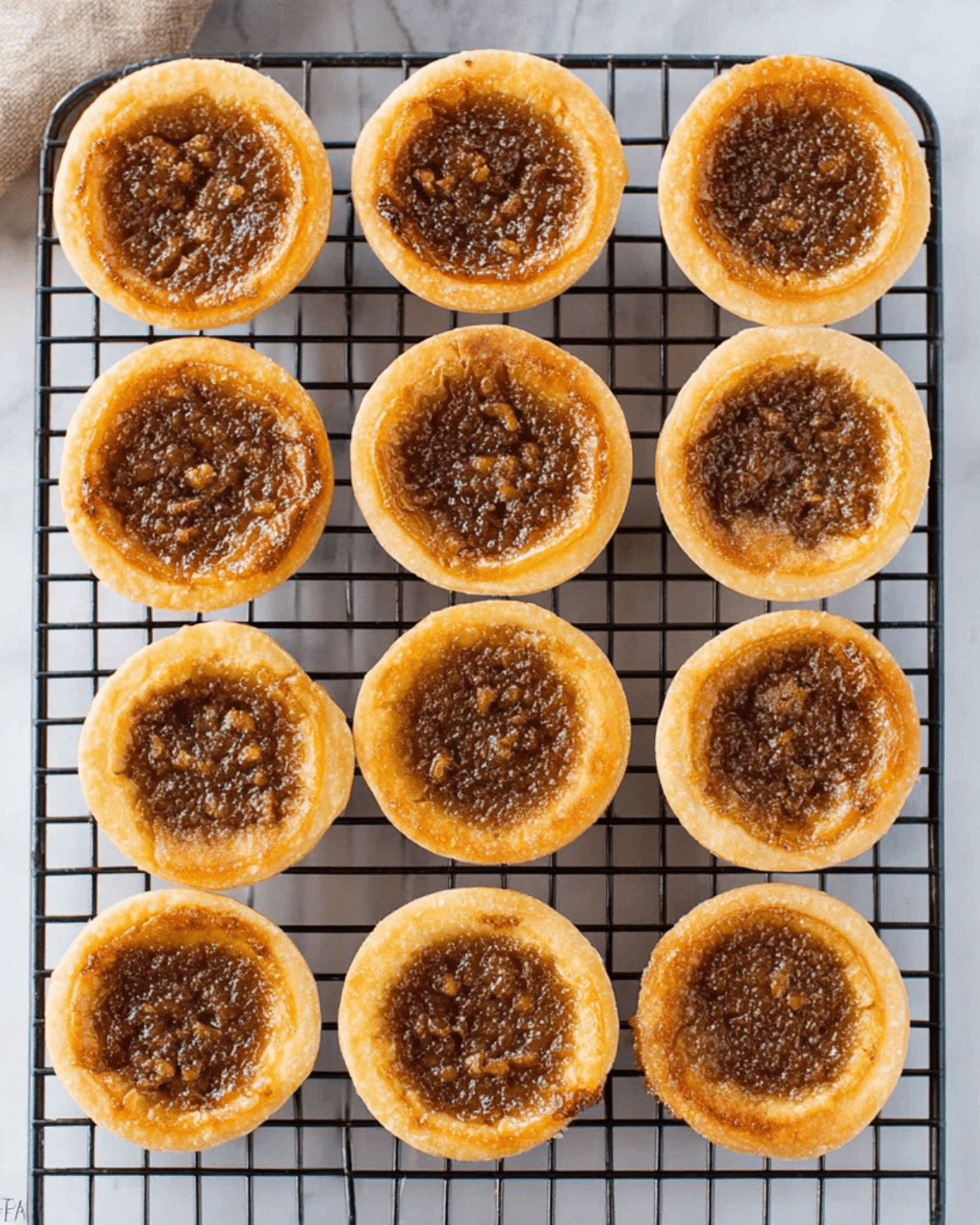 Classic Butter Tarts with golden crusts and gooey brown sugar filling cooling on a wire rack.
