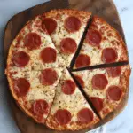 Pepperoni pizza made with sourdough discard pizza crust, sliced and served on a wooden board.