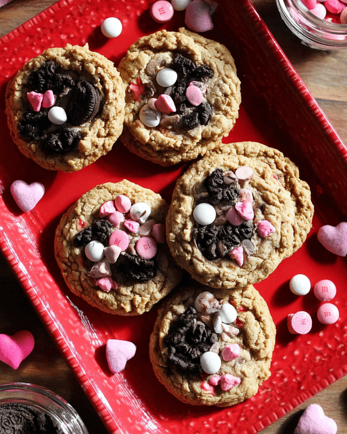 Valentine's Day Oreo M&M cookies topped with crushed Oreos and pink, red, and white M&Ms on a red tray.